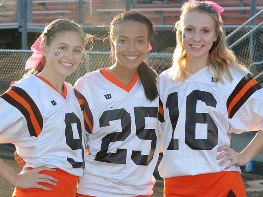 Three girls in football uniforms smiling