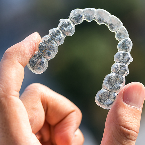 Hand holding a clear aligner