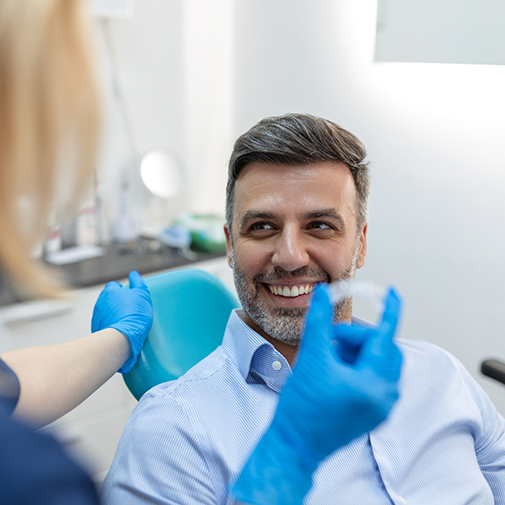 Patient looking at orthodontist holding aligner