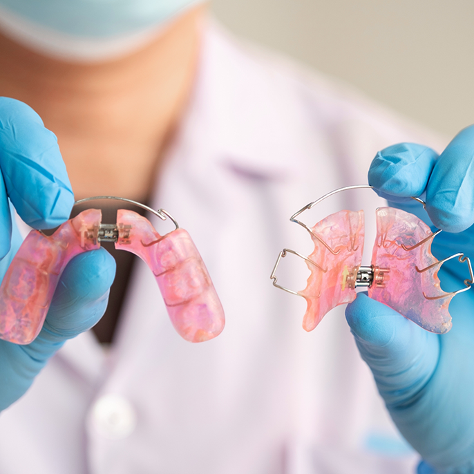 Gloved hands holding two orthodontic appliances in Columbus