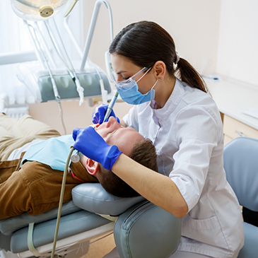 Orthodontist treating a patient lying back in chair