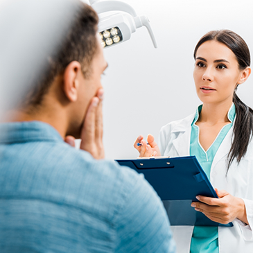 Orthodontist holding clipboard and talking to patient