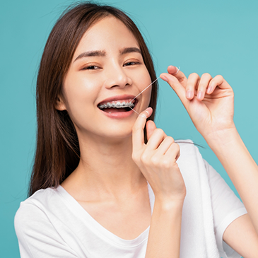 Woman with braces flossing under brackets and wires