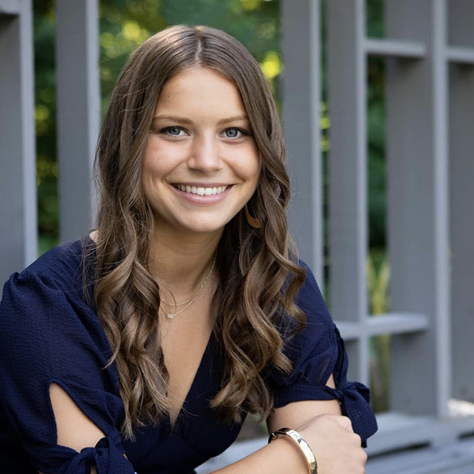 Woman sitting in front of fence and smiling