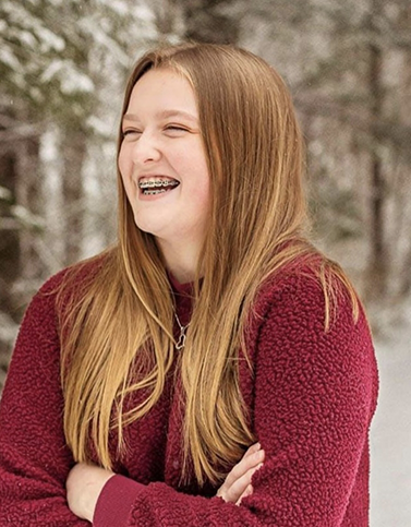 Woman with braces smiling with arms folded