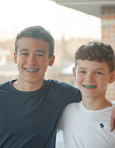 Two young boys smiling with braces