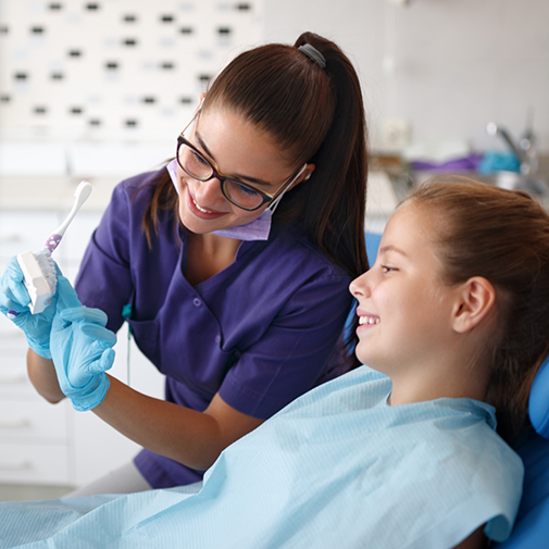 Orthodontist showing child patient model of teeth