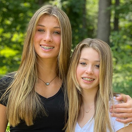 Girl with braces hugging other girl with braces from side