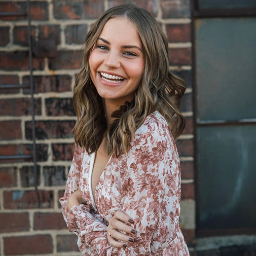 Woman with floral shirt in front of brick wall