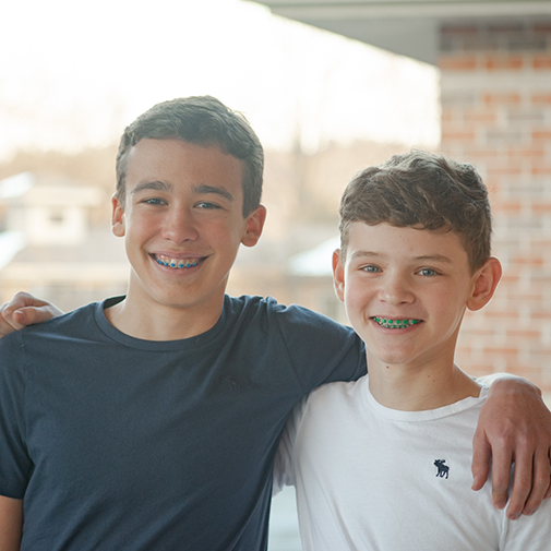 Two boys with braces with arms around each other